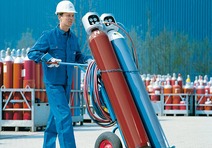 Man transporting gas cylinders using steel trolley